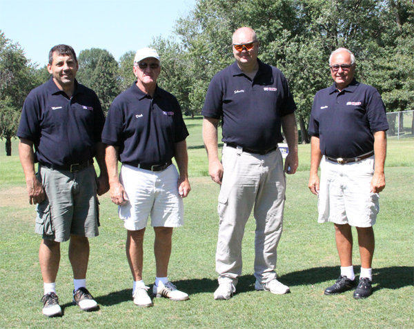 Four men pose for a group photo on the golf course