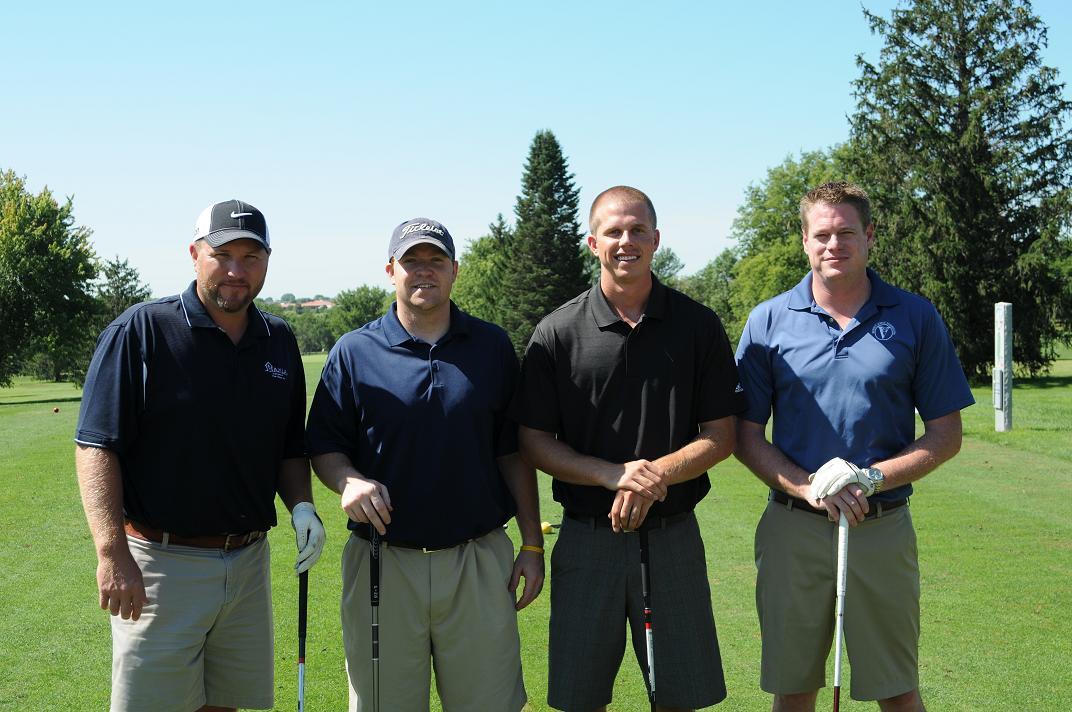 Four men on the golf course posing for a group photo