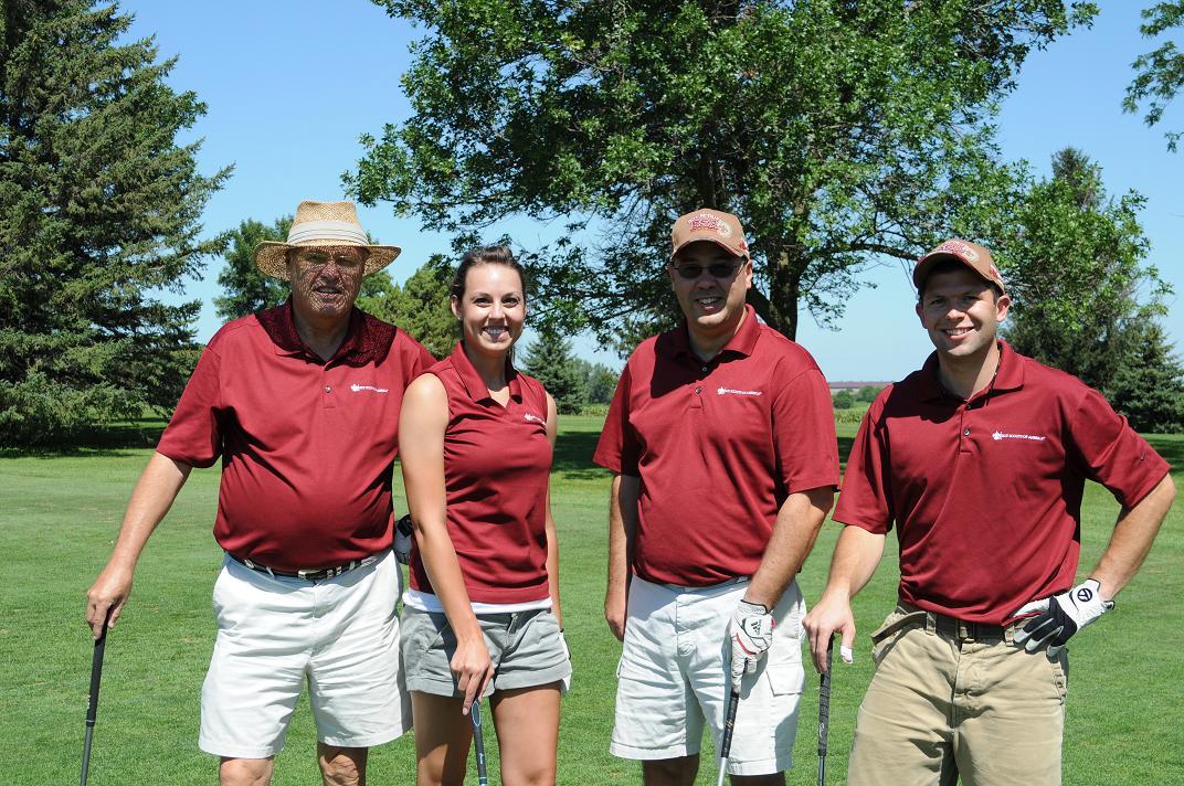 Four golfers in red polos pose for a group photo together