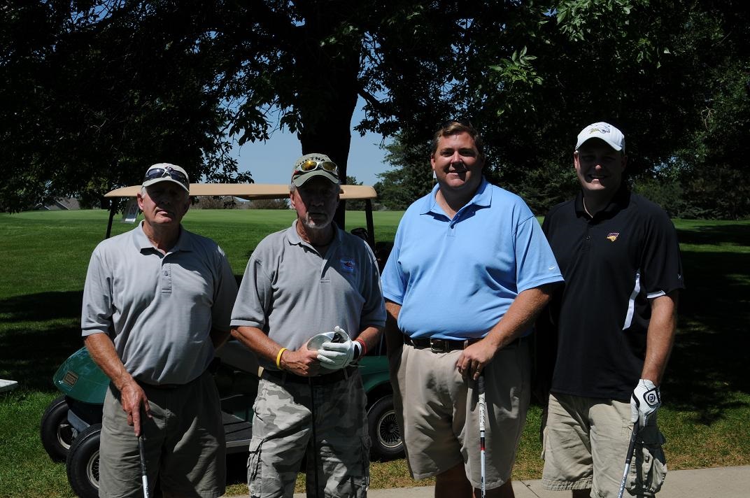 Four male golfers pose for a group photo