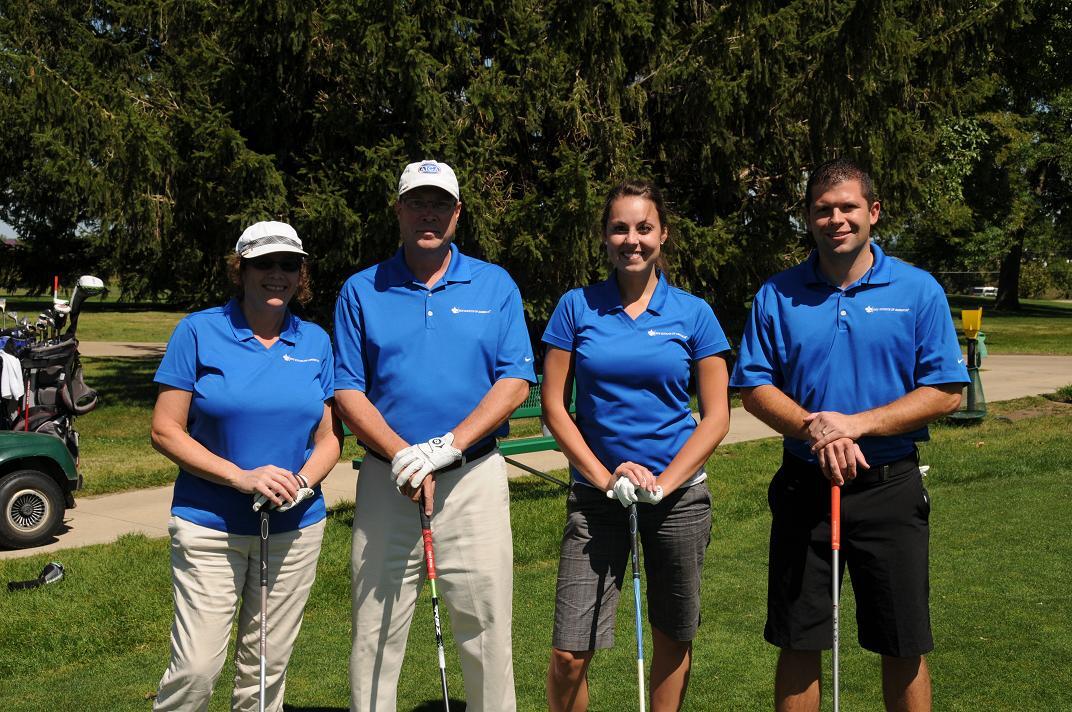 Four golfers posing with their golf clubs.