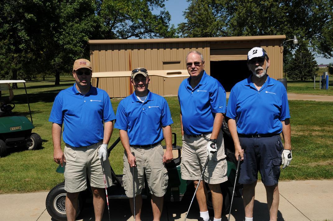 A group of people posing with golf clubs wearing golf gear