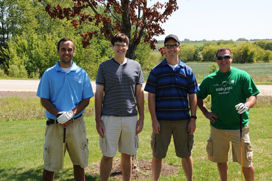 Four people smiling and posing for a photo on the golf course