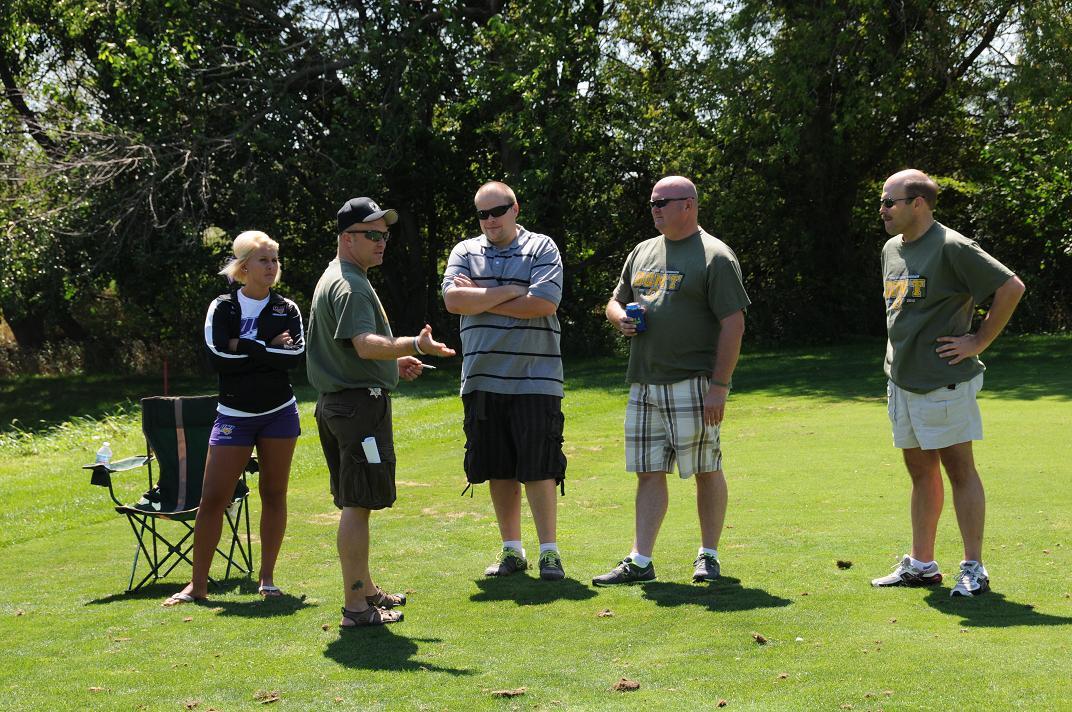 People talking and standing on the golf course in a group