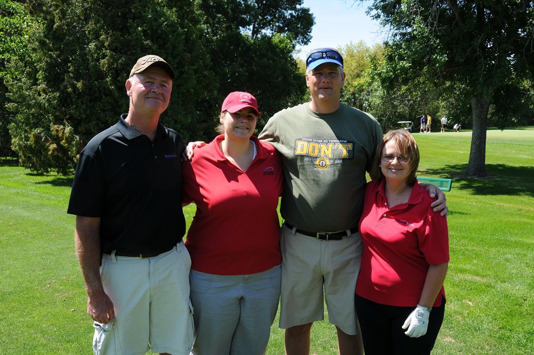 Four people pose for a photo on the golf course