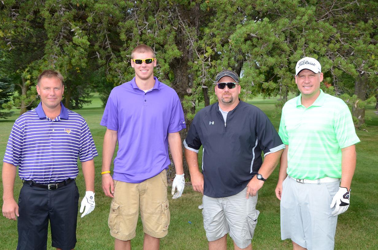 Men in golf gear pose for a photo on the golf course