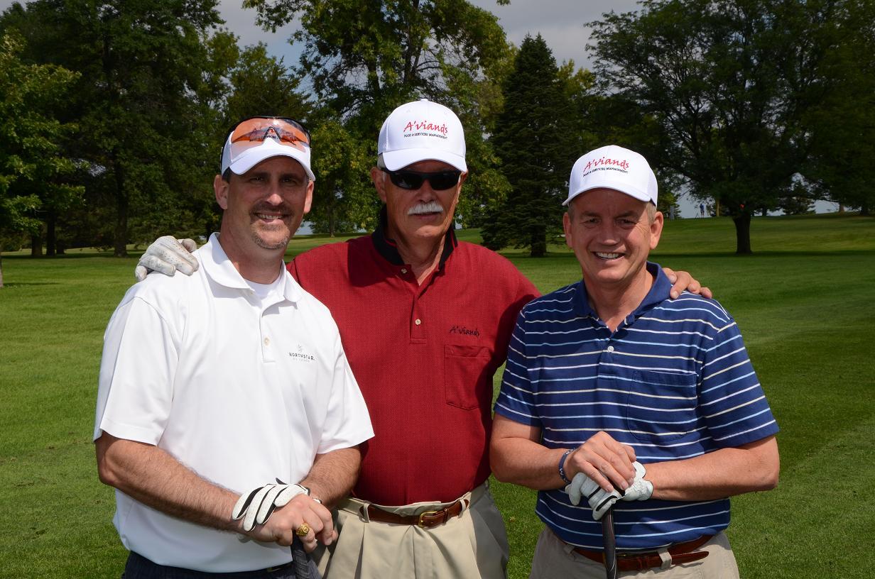 Three men pose for a photo on the golf course together