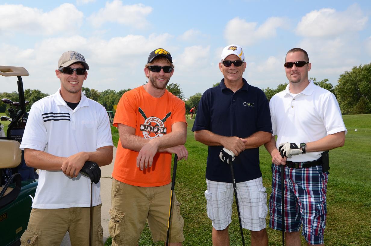 Men leaning on golf clubs pose for a photo