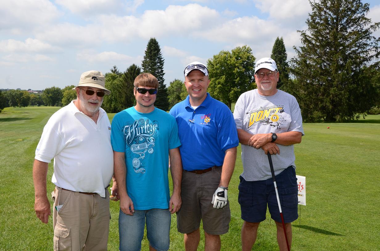 Four men smile for a photo on the golf course