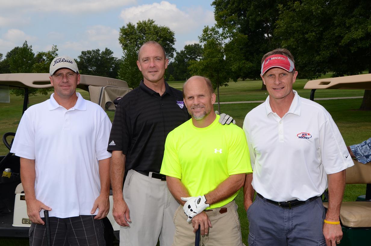 Men in a group smile and pose for a photo on the golf course