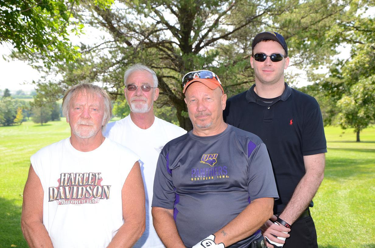 Four men in a group posing for a photo on the golf course