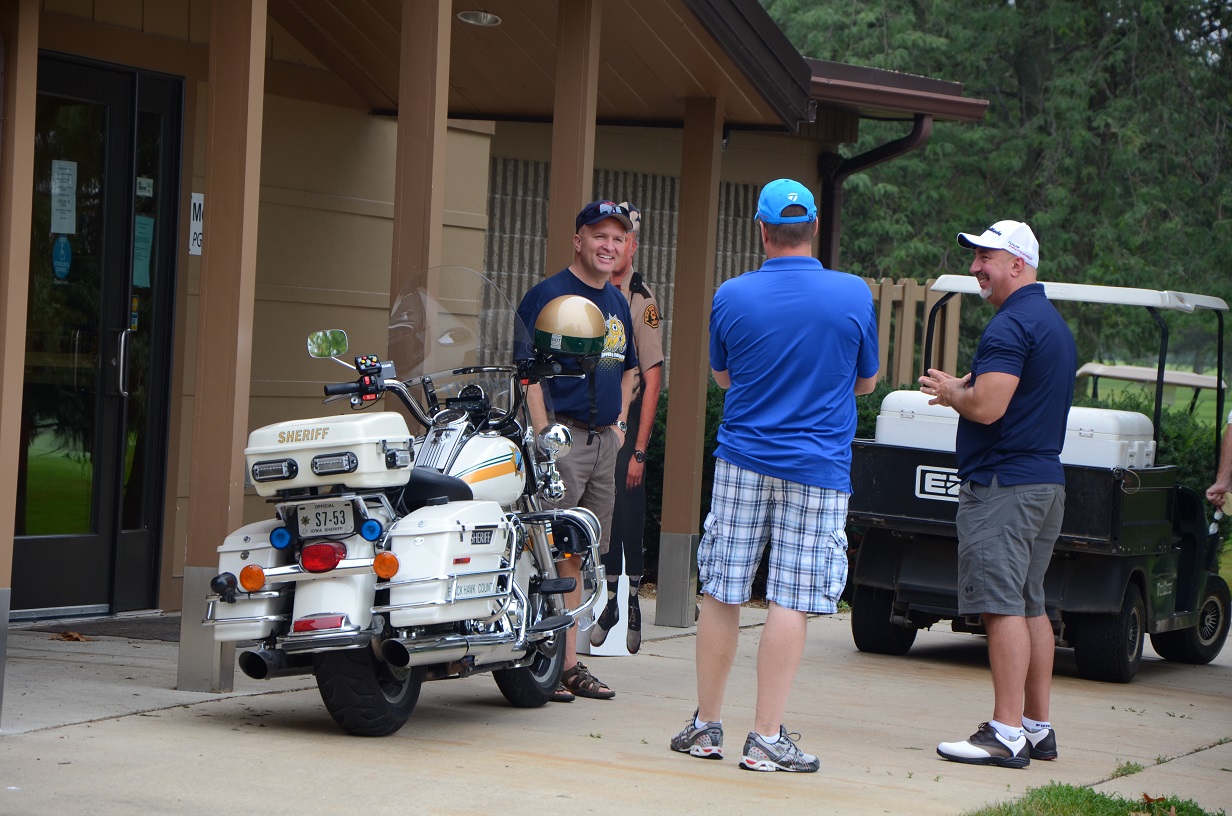 Three men chatting and standing by motorcycle