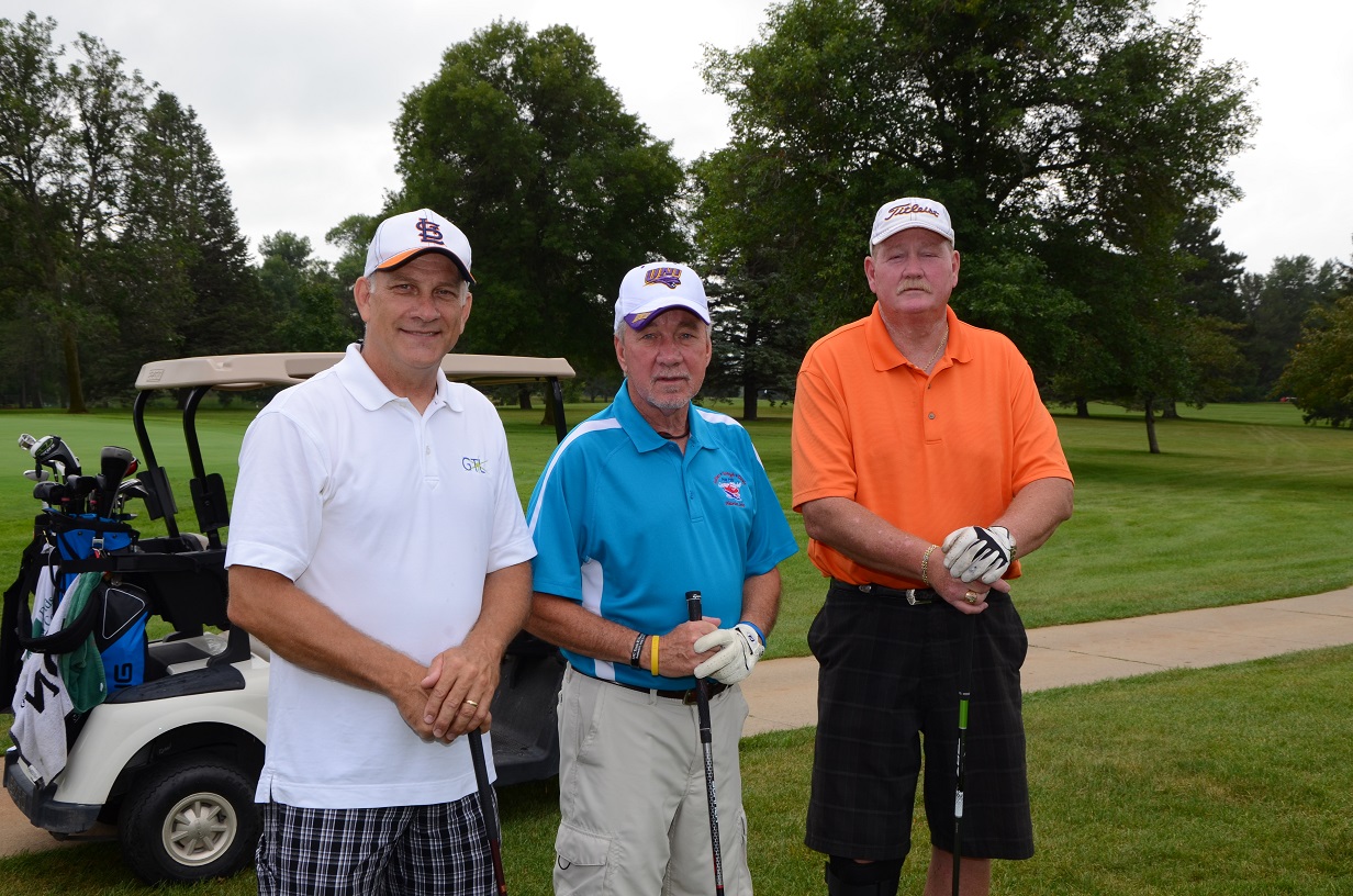 Three men in golf gear pose for a photo outdoors