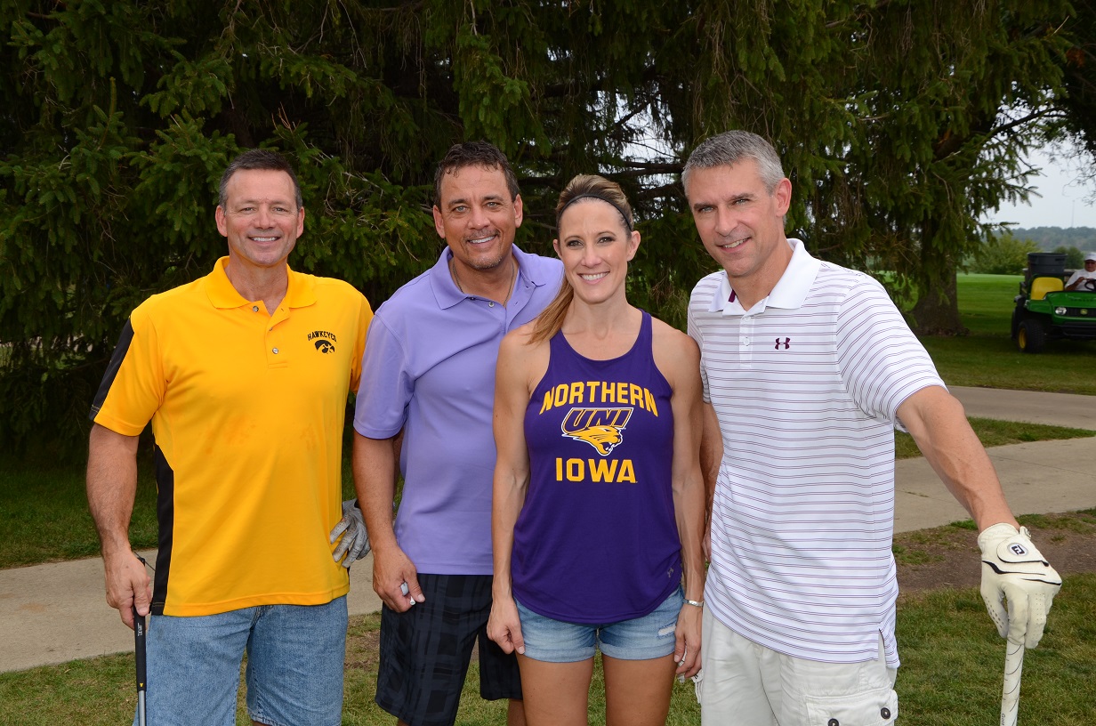 Four people pose for a photo together on the golf course