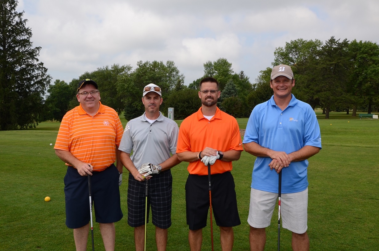 Men posing outdoors at the golf course for a photo