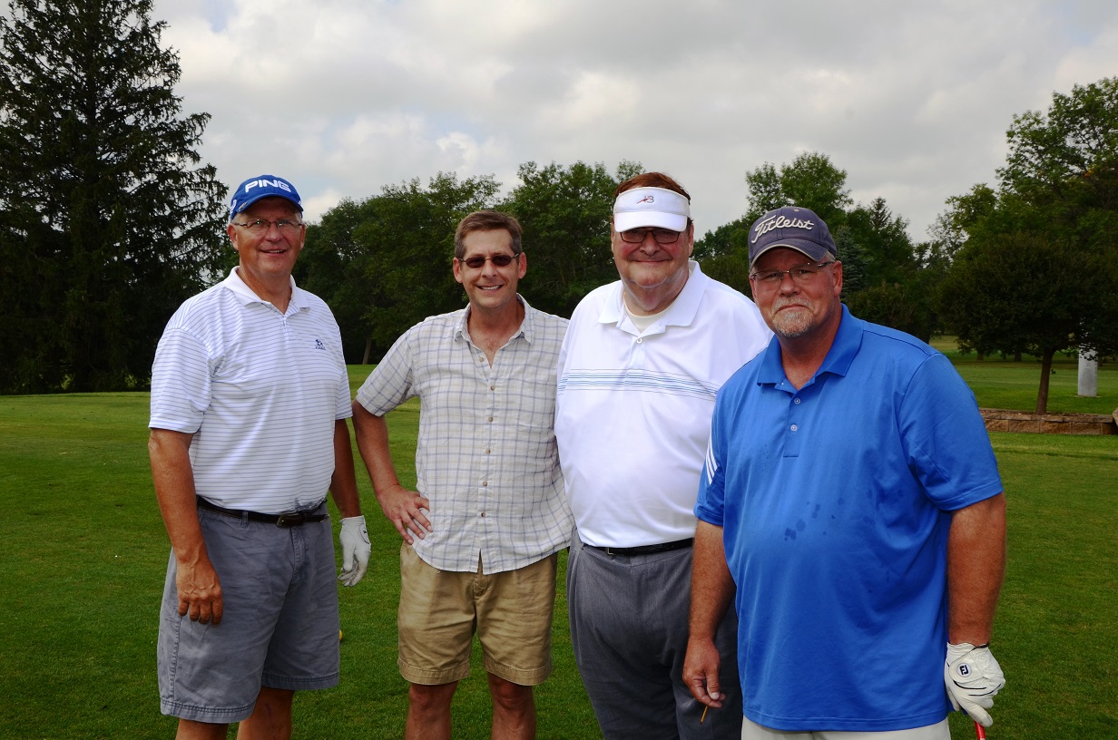 Golfers in a group on the course posing for a photo