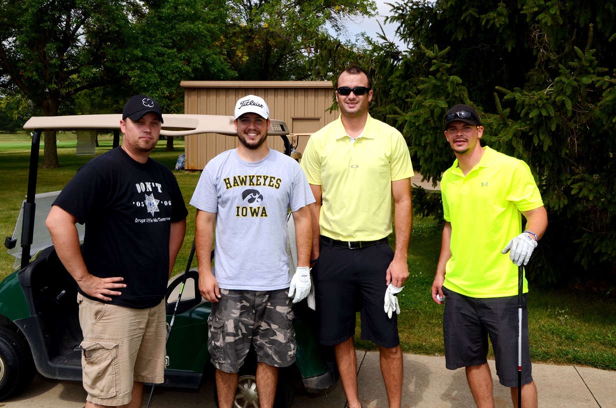 Golfers by golf cart pose for a photo