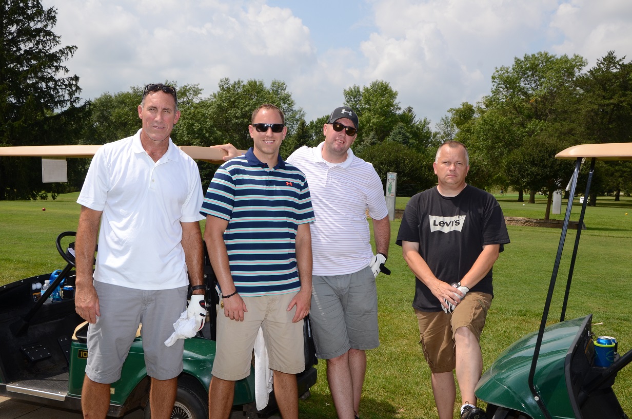 Golfers in golf gear posing for a photo outside