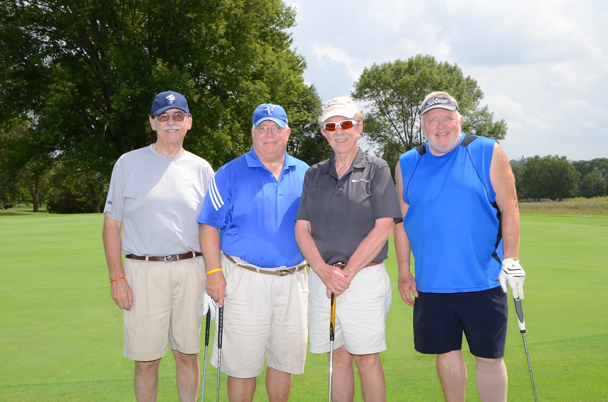 Four golfers take a photo outside on the course