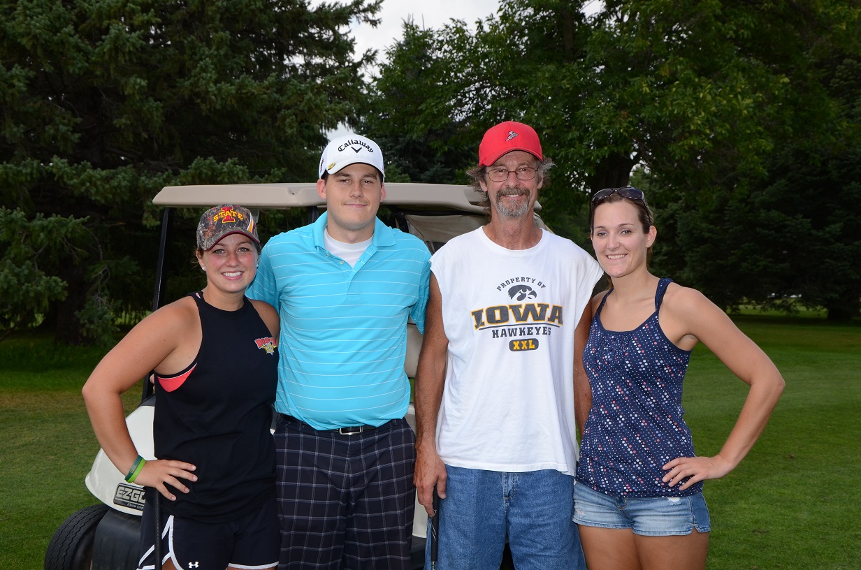 Four people get their picture taken on the golf course