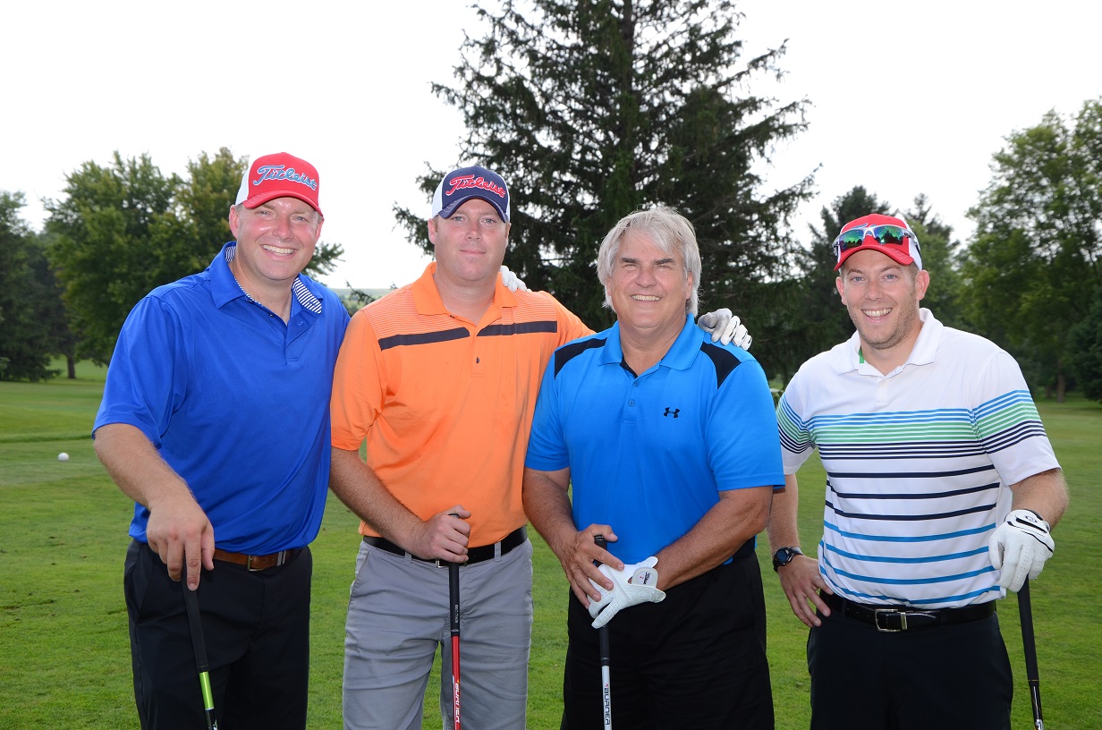 Four men pose for a photo with their golf clubs