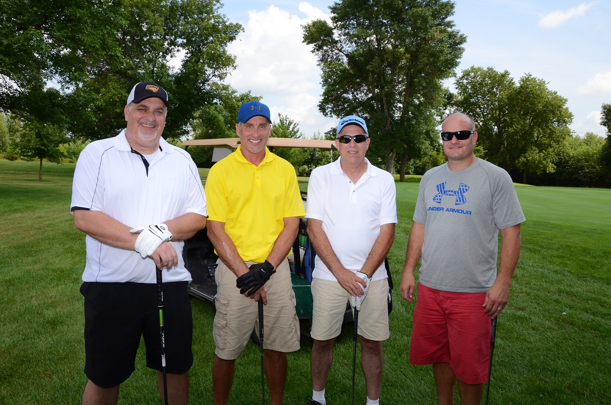 Men holding golf clubs pose for a photo