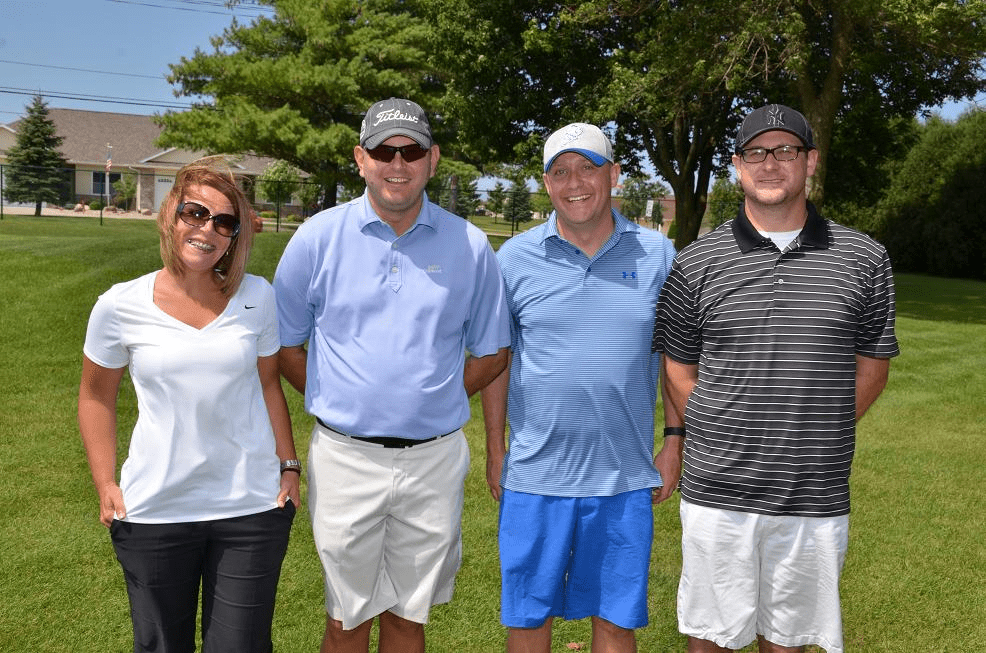 Four people in golf gear posing for a photo