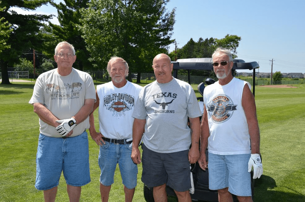 Four men posing for a photo on the golf course