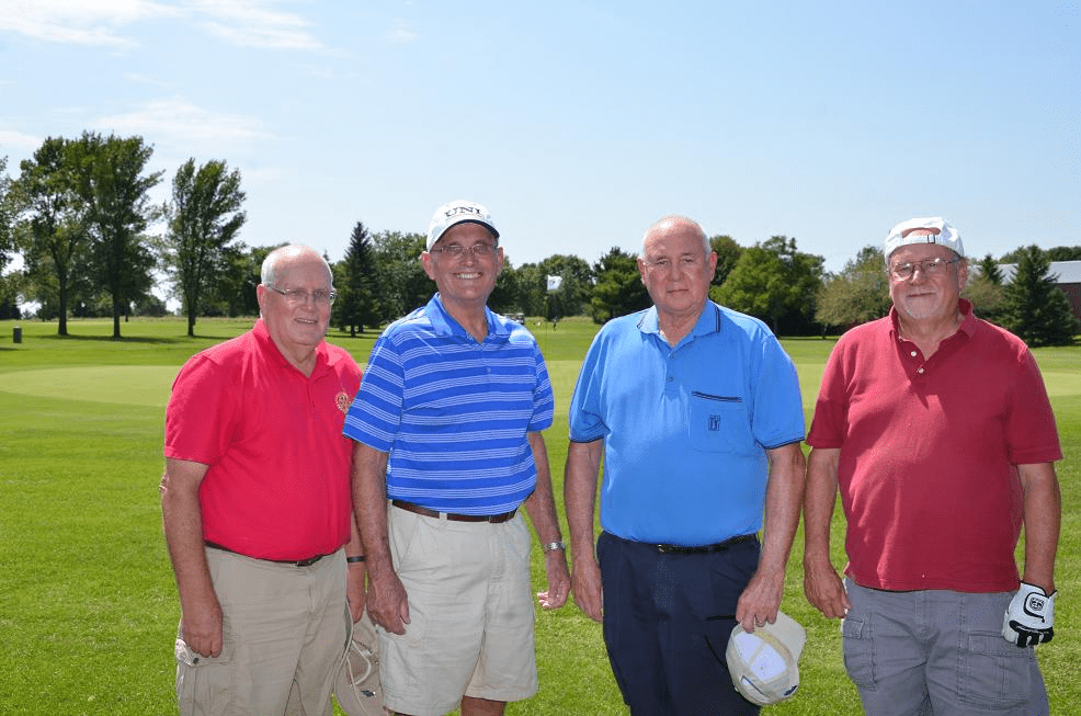 Men in golf gear posing for a picture on the golf course