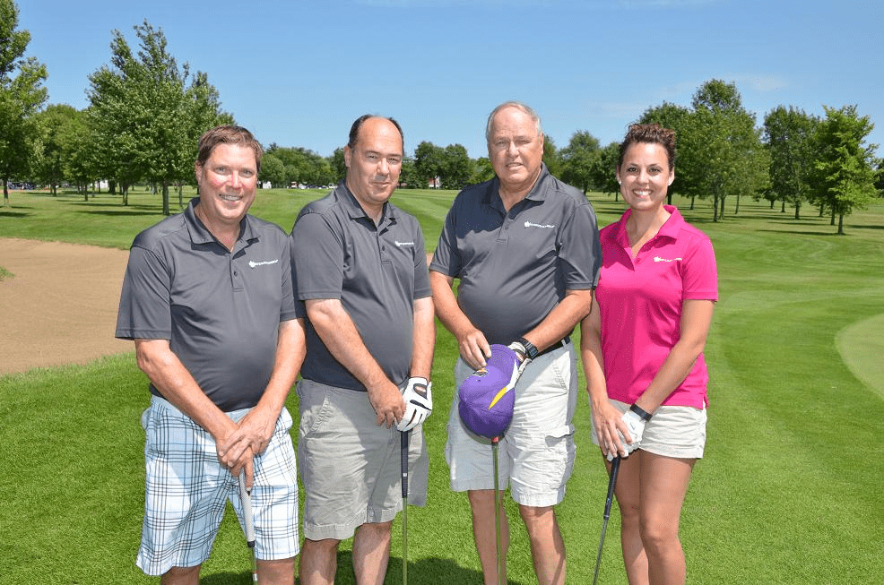 Golfers posing with clubs on the golf course.