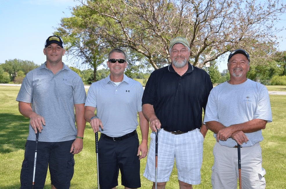 Four people posing for a photo on the golf course