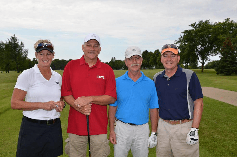 Group of 3 men and 1 woman in golf gear posing for a photo