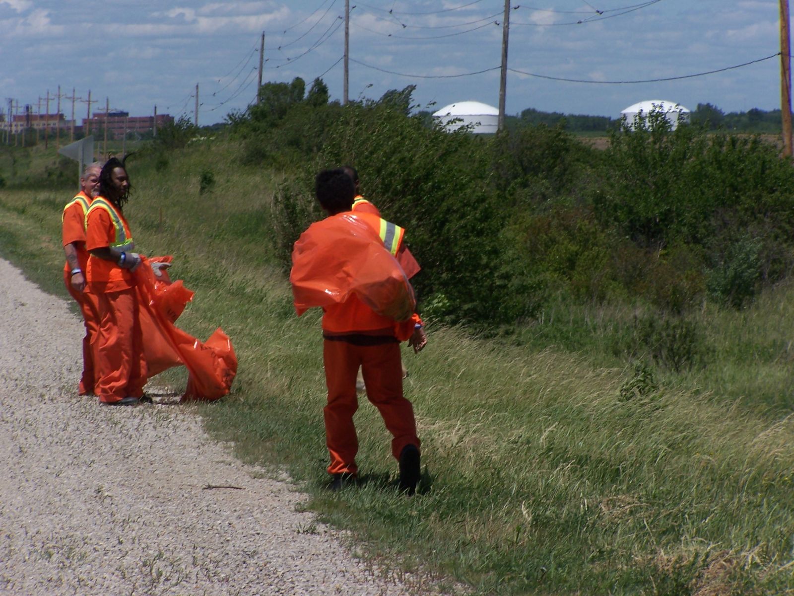 Three inmates cleaning up the side of the road