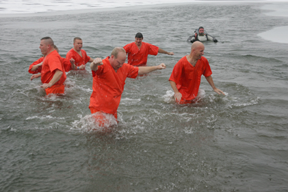 People in orange outfits in the water during polar plunge