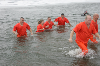 People dressed in orange outfits are waist deep in water